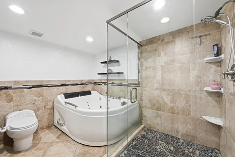 a bathroom with a white bath tub a toilet and a shower