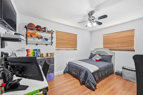 a bedroom with a bed a computer on desk and a dresser next to a window