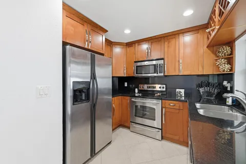 a kitchen with stainless steel appliances granite countertop a stove a sink and a refrigerator