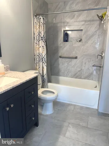 a bathroom with a granite countertop bathtub sink vanity mirror and toilet