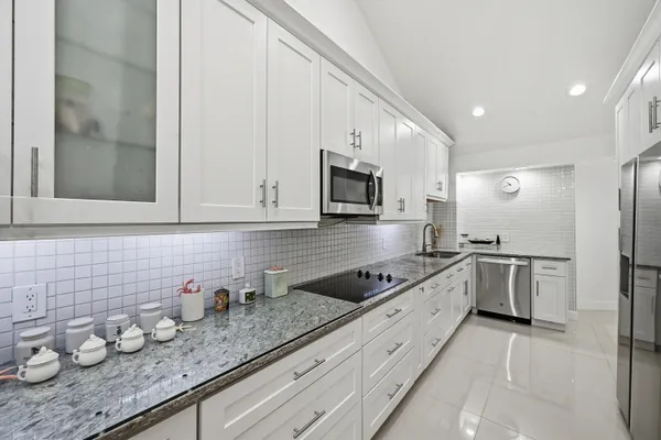 a kitchen with granite countertop a sink stainless steel appliances and cabinets