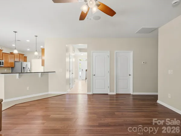 a kitchen with stainless steel appliances granite countertop a stove top oven a sink a dining table and chairs with wooden floor