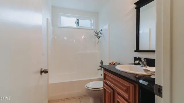 a bathroom with a granite countertop sink a toilet a mirror and shower