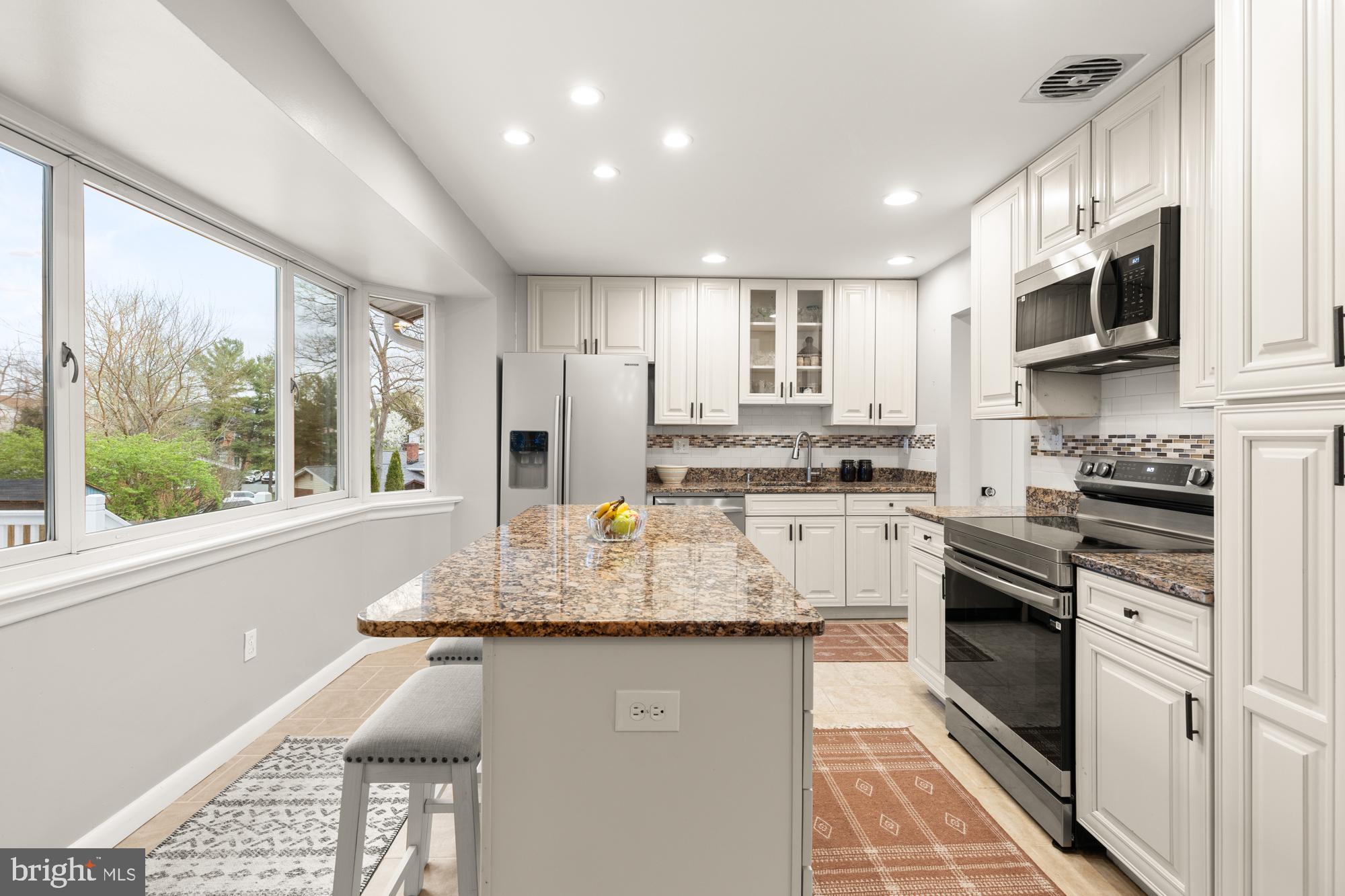 2407 Harmon Road Silver Spring, MD 20902 - Photo 9 of 39 a kitchen with kitchen island granite countertop a stove top oven a sink a counter space and cabinets