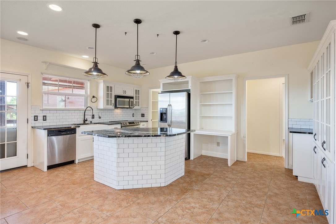 845 Rutherford Fischer, TX 78623 - Photo 7 of 39 a kitchen with stainless steel appliances granite countertop a sink a stove a refrigerator and white cabinets
