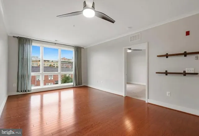 a view of an empty room with wooden floor and a window