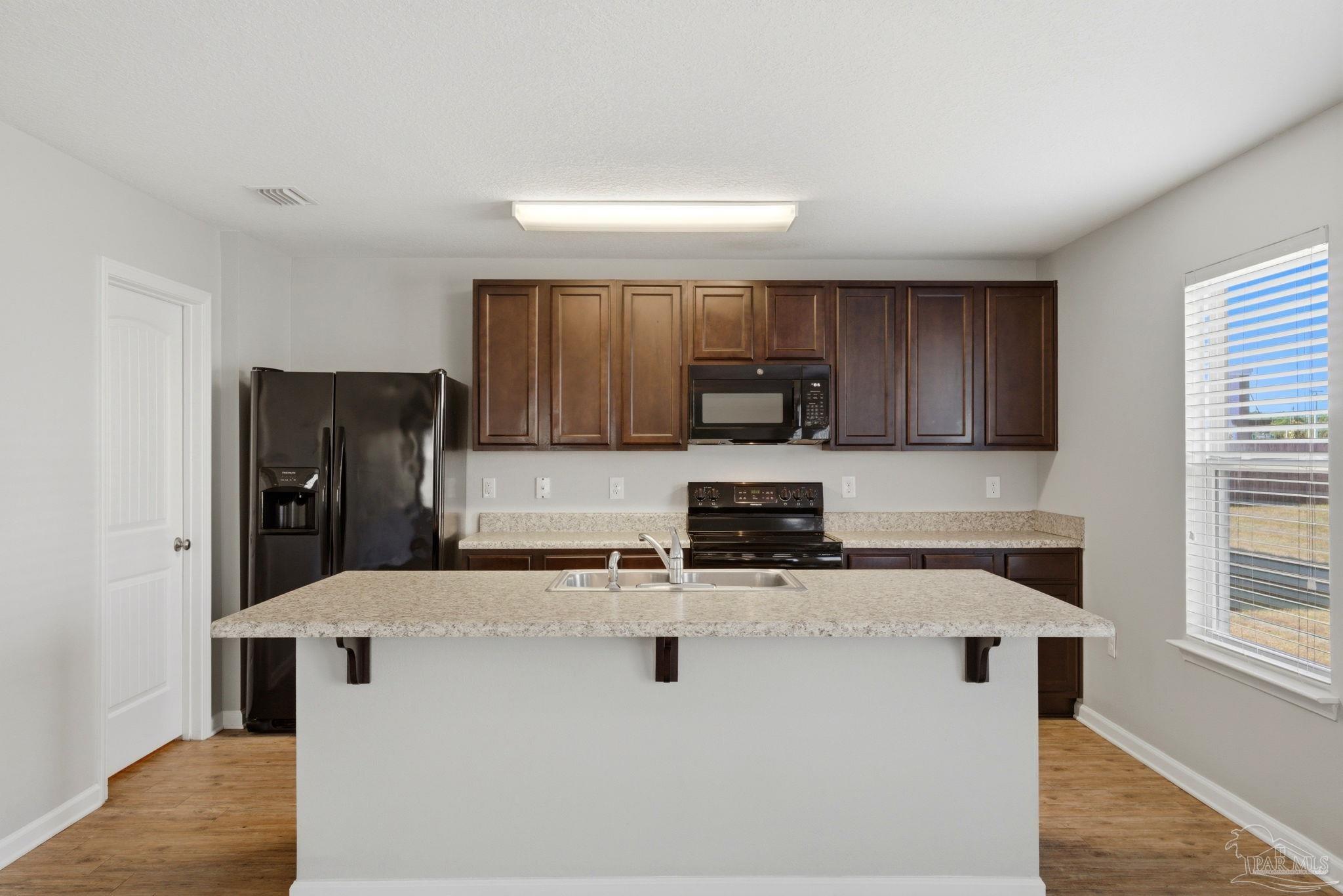5881 Bay Tree Court Milton, FL 32570 - Photo 10 of 51 a kitchen with kitchen island a sink a stove a microwave and refrigerator
