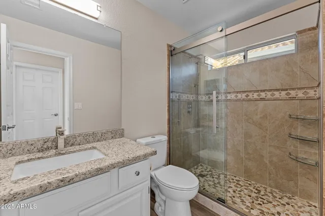 a bathroom with a granite countertop sink toilet and shower