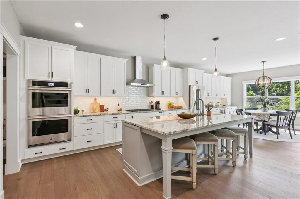 102 Bartlett Lane Wexford, PA 15090 - Photo 16 of 40 a kitchen with stainless steel appliances kitchen island granite countertop a table chairs and a wooden floor