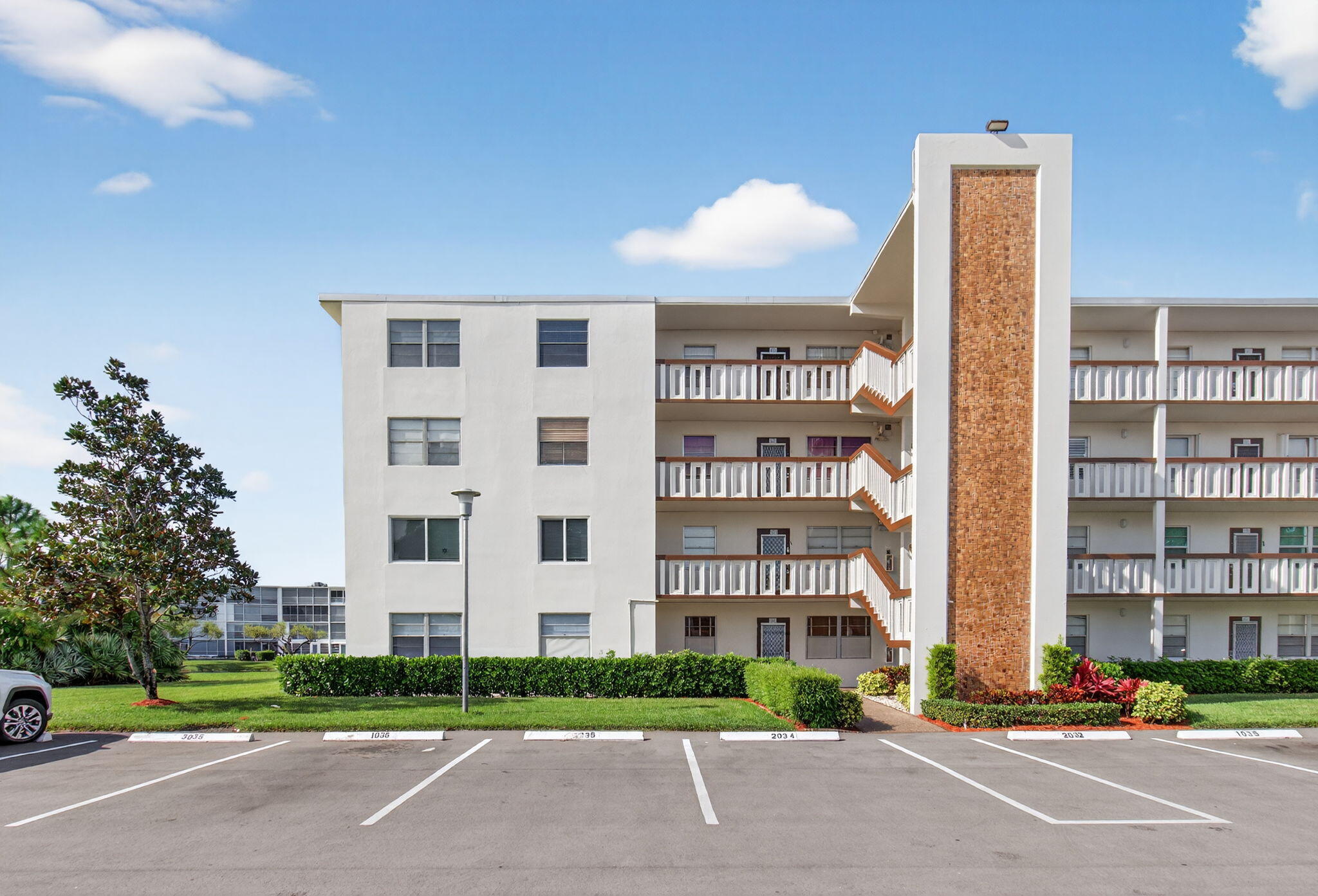 1036 Hythe B, Unit B Boca Raton, FL 33434 - Photo 48 of 53 a view of a tall building next to a yard