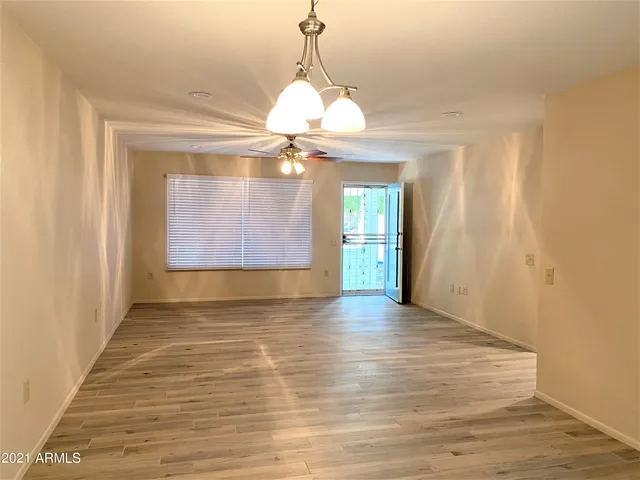 a view of an empty room with window and wooden floor