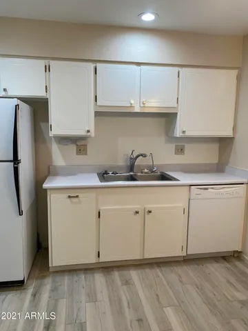 a kitchen with granite countertop white cabinets and refrigerator