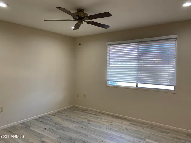 a view of empty room with wooden floor and fan