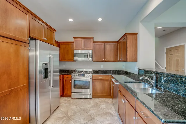 a kitchen with stainless steel appliances granite countertop a sink stove and refrigerator