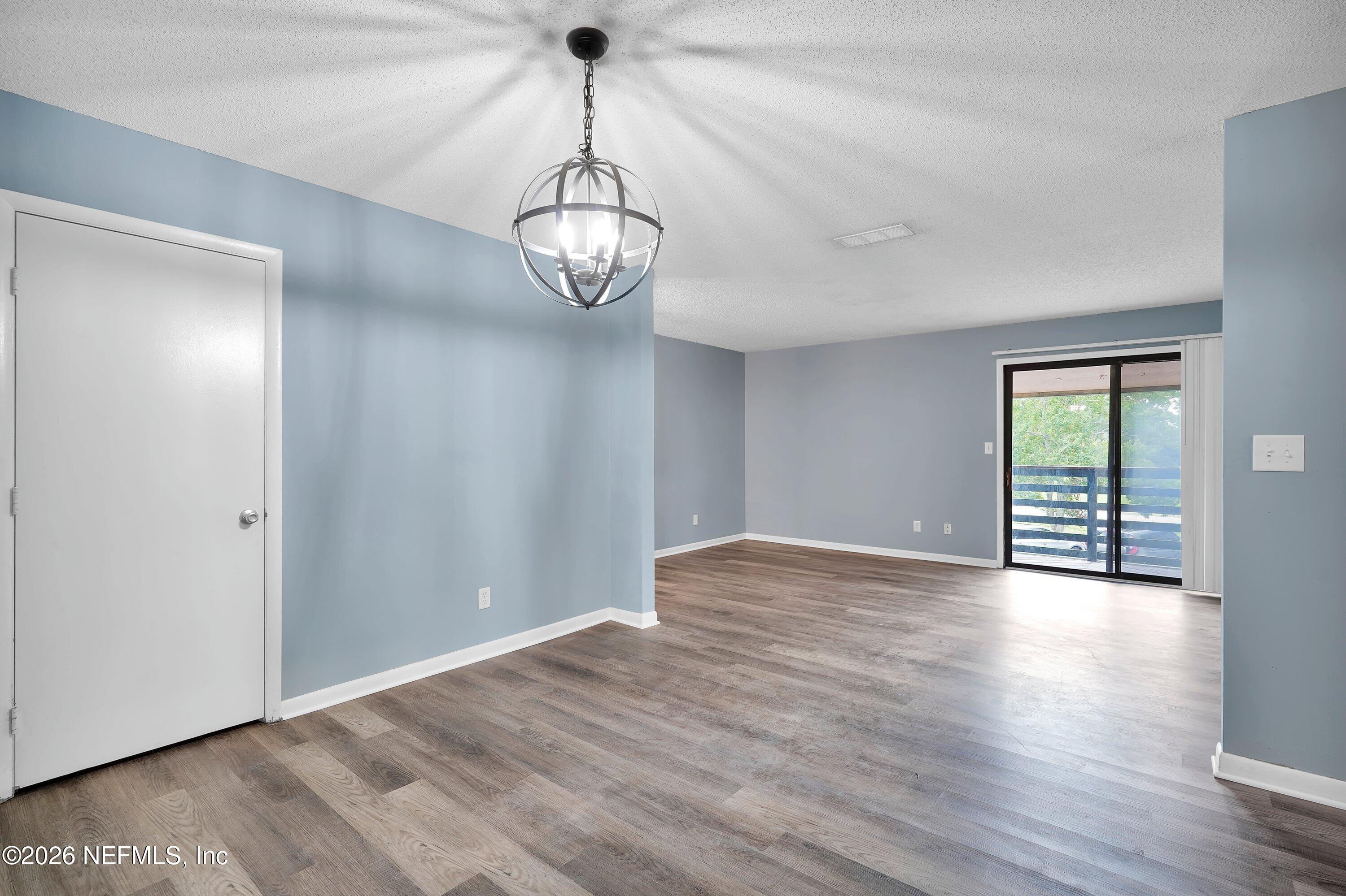 3765 Crown Point Road, Unit 13 Jacksonville, FL 32257 - Photo 15 of 37 a view of an empty room with wooden floor and chandelier