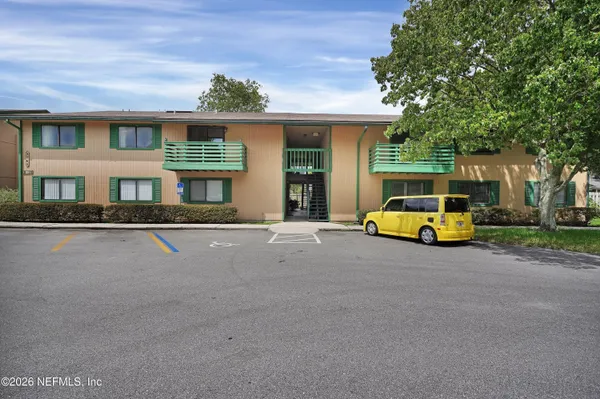 a view of an empty room with wooden floor and a ceiling fan