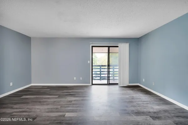 a view of an empty room with wooden floor and chandelier
