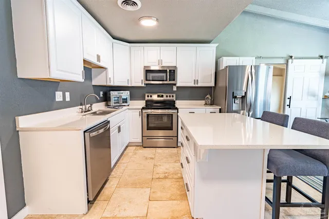 a white kitchen with a stove a sink a microwave and a refrigerator