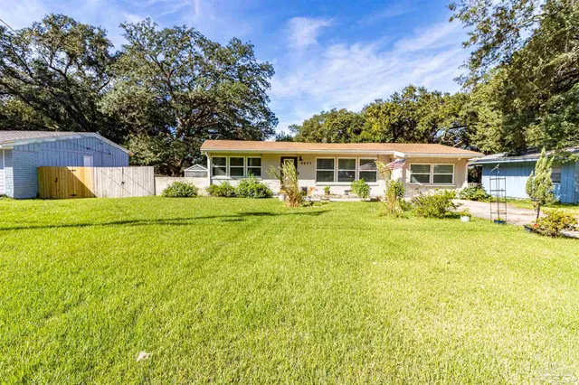 a front view of a house with a garden and trees