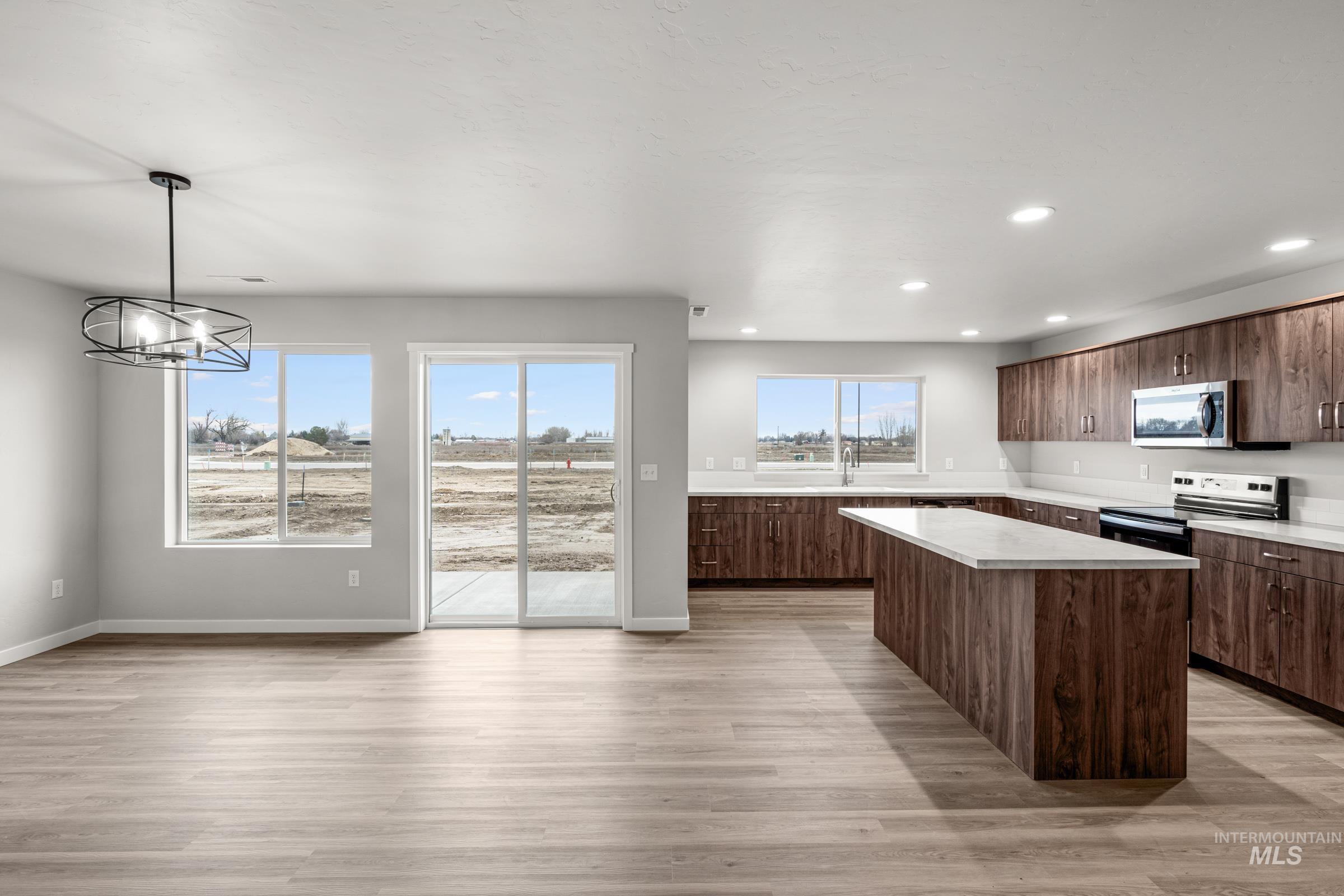 1651 Dyer Street Middleton, ID 83644 - Photo 7 of 28 Kitchen with light countertops, a kitchen island, dark wood finish cabinetry, light wood finished floors, and stainless steel appliances