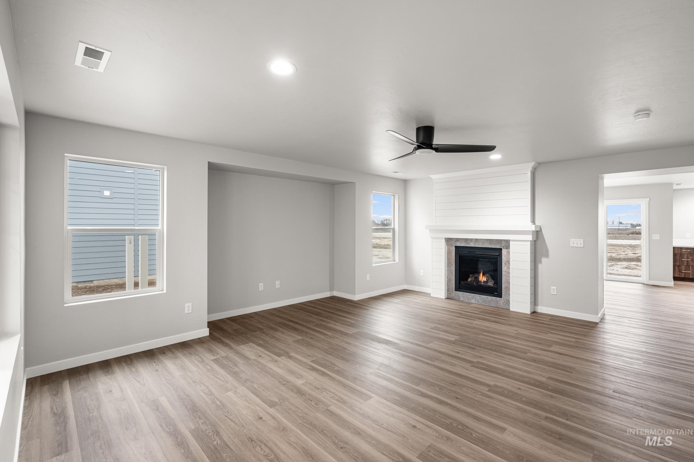 1651 Dyer Street Middleton, ID 83644 - Photo 8 of 28 Unfurnished living room featuring wood finished floors, a ceiling fan, a glass covered fireplace, and recessed lighting