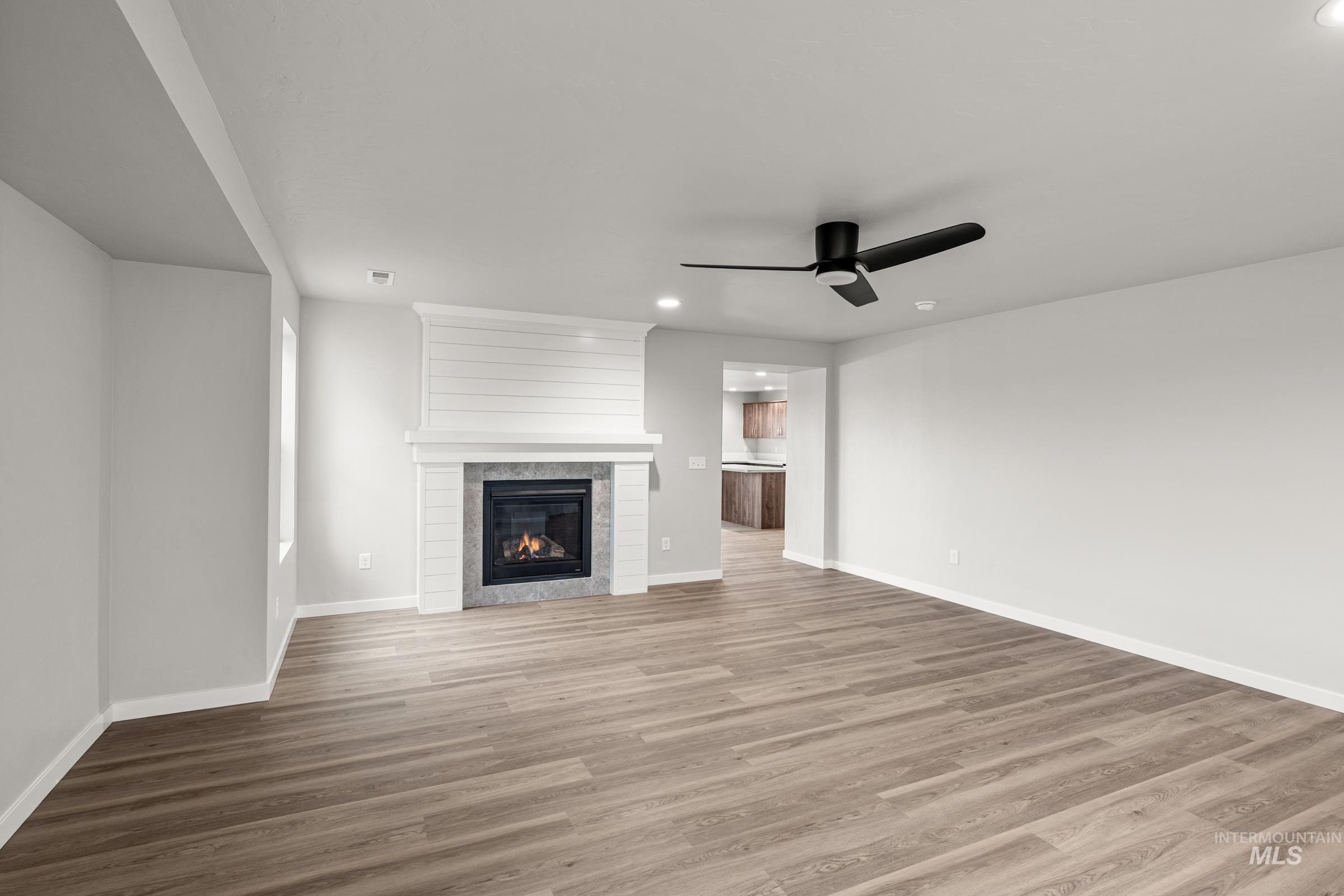 1651 Dyer Street Middleton, ID 83644 - Photo 9 of 28 Unfurnished living room with a ceiling fan, dark wood-style flooring, a tiled fireplace, and recessed lighting