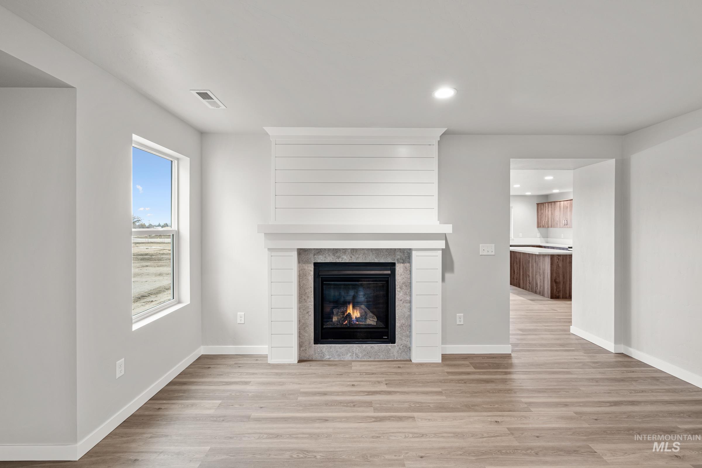 1651 Dyer Street Middleton, ID 83644 - Photo 10 of 28 Unfurnished living room with light wood-style floors, a tiled fireplace, and recessed lighting