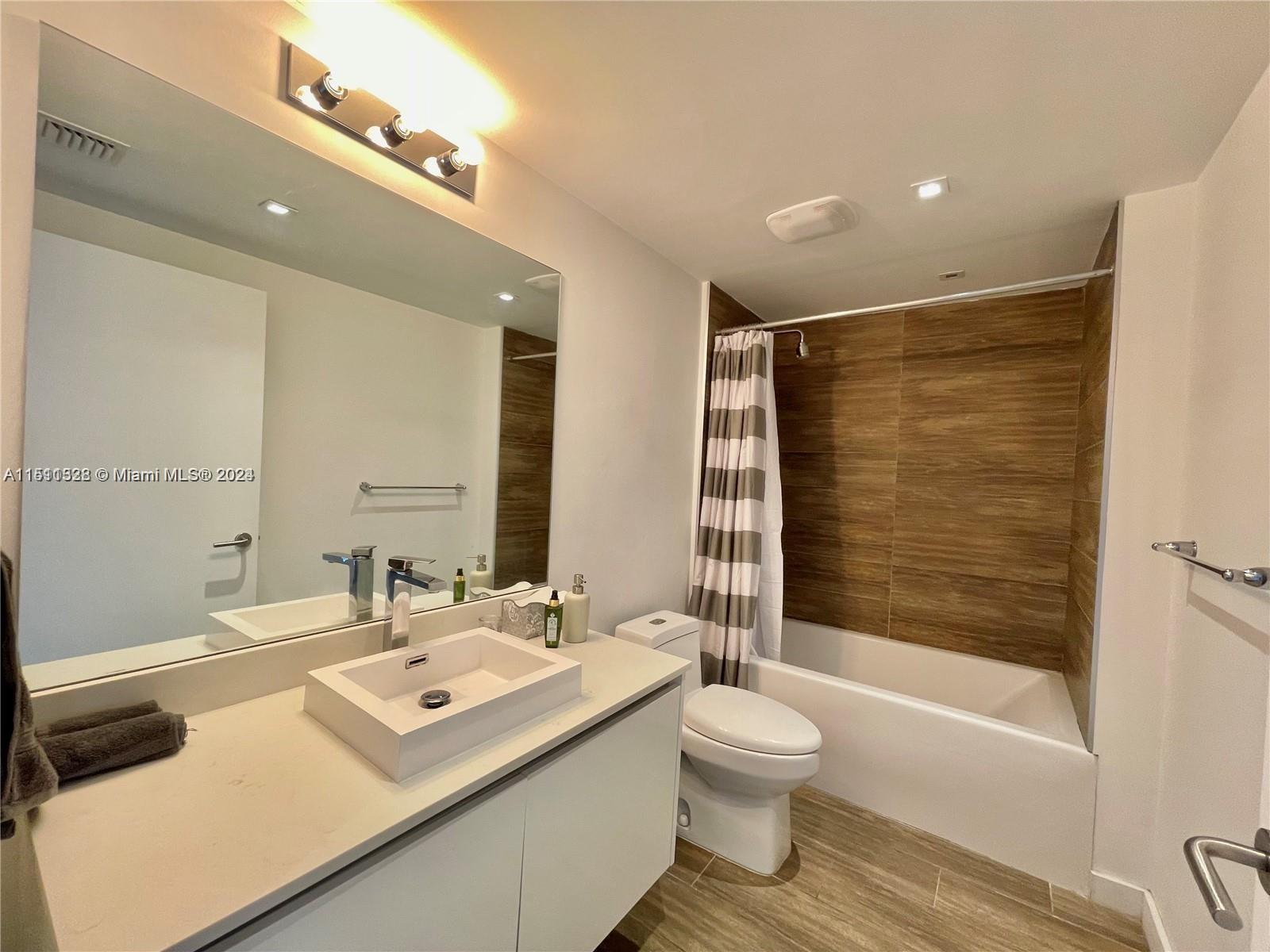 1600 Southwest 1st Avenue, Unit 511 Miami, FL 33129 - Photo 6 of 10 a bathroom with a double vanity sink toilet mirror and bathtub