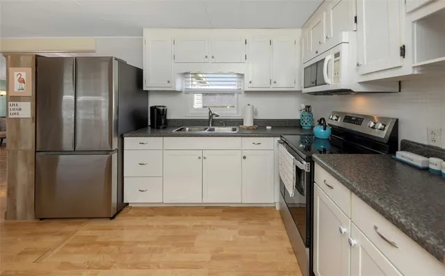 a kitchen with stainless steel appliances granite countertop a sink refrigerator and cabinets
