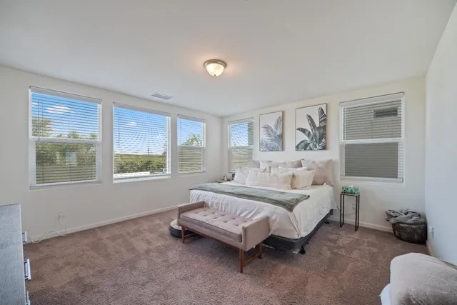 a spacious bedroom with a bed a table and windows