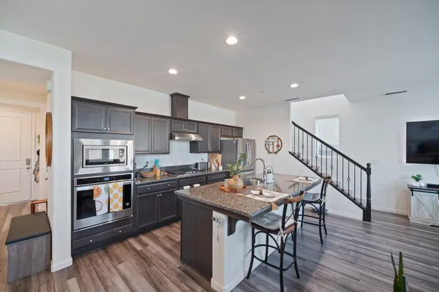 a kitchen with stainless steel appliances kitchen island granite countertop a table chairs stove and refrigerator