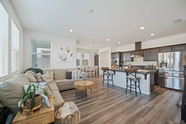 a living room with furniture kitchen view and a large window