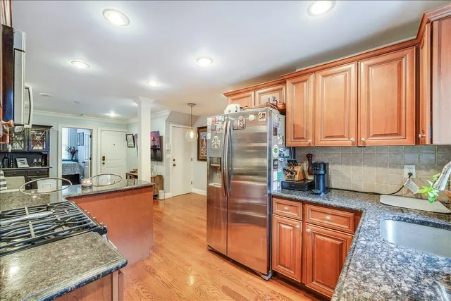 a kitchen with stainless steel appliances granite countertop a refrigerator a stove and a sink with cabinets