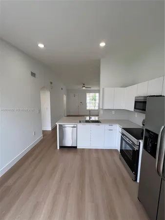 a large kitchen with stainless steel appliances a large counter top a stove a sink and a refrigerator
