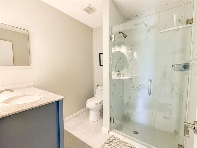 a bathroom with a shower sink mirror and toilet