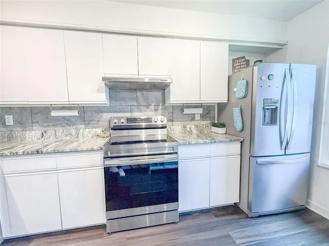 a kitchen with a refrigerator stove and wooden cabinets