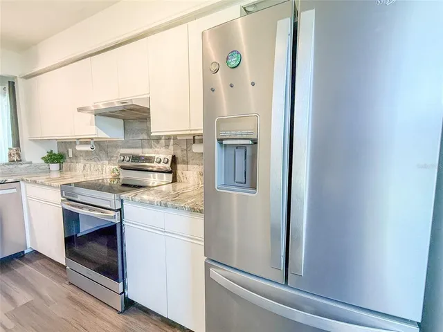 a kitchen with stainless steel appliances granite countertop a refrigerator and a stove