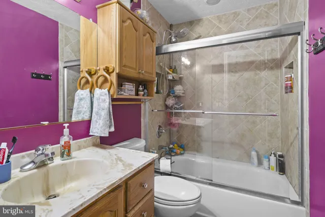 a bathroom with a granite countertop bathtub shower sink vanity mirror and toilet