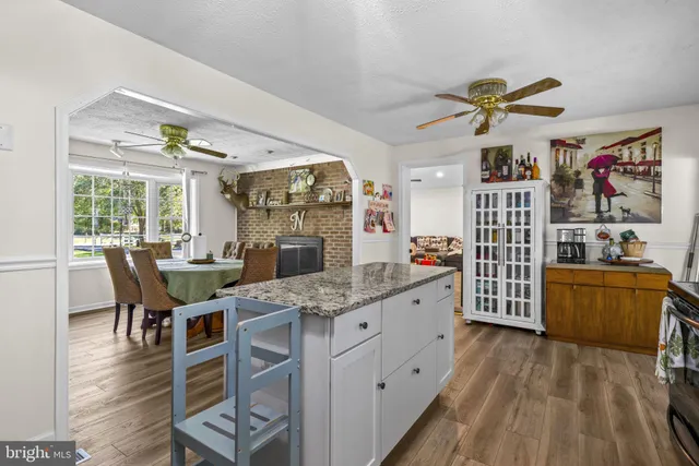a kitchen with stainless steel appliances granite countertop a stove a sink dishwasher and a dining table with wooden floor