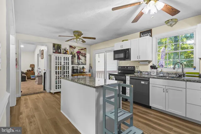 a kitchen with stainless steel appliances granite countertop a stove top oven a sink dishwasher and a refrigerator with wooden floor