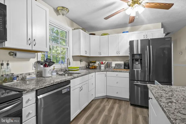 a kitchen with granite countertop stainless steel appliances a sink stove and refrigerator
