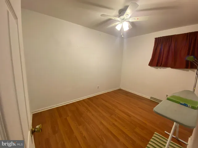 an empty room with wooden floor and a ceiling fan