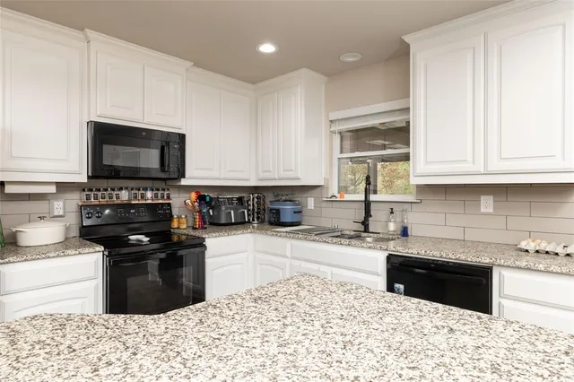 a kitchen with granite countertop a stove a sink and a microwave