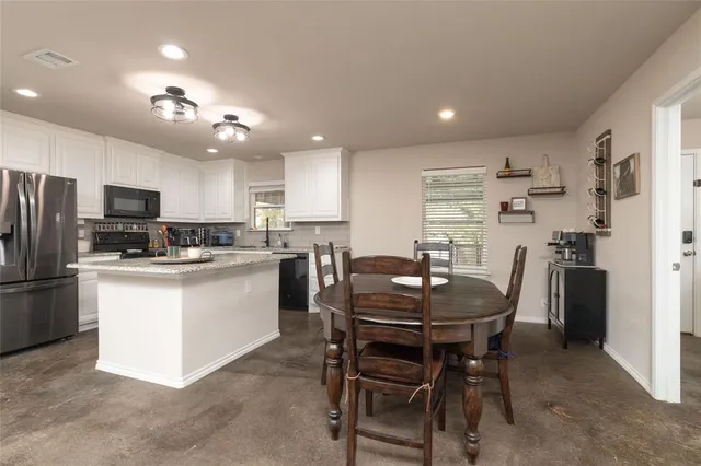 a kitchen with a refrigerator a stove a sink a dining table and chairs