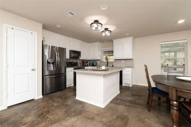 a kitchen with a refrigerator a microwave a dining table and chairs