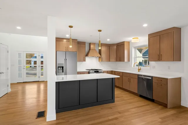a large kitchen with stainless steel appliances a sink and wooden floor