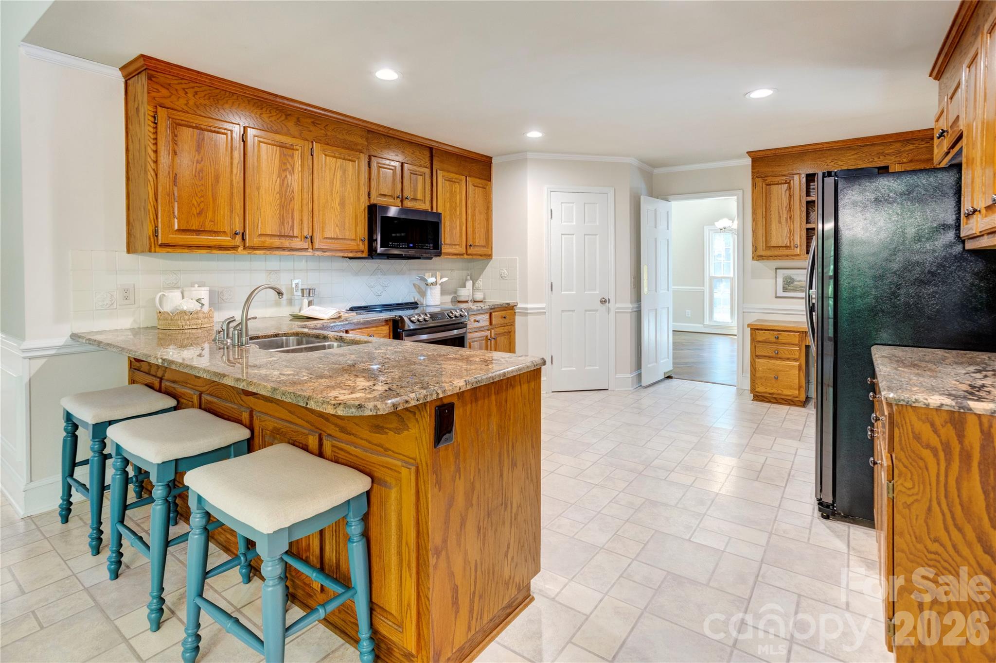 1188 Fawn Ridge Road Northwest Concord, NC 28027 - Photo 12 of 38 a kitchen with granite countertop a table chairs microwave and sink