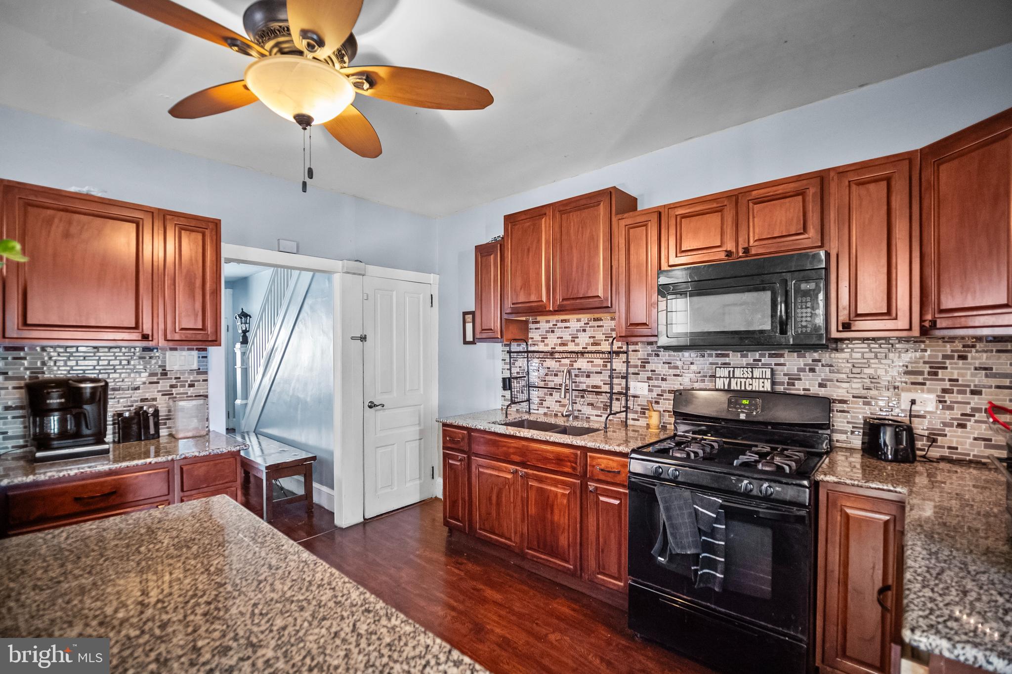 614 Maple Street Reading, PA 19602 - Photo 9 of 23 a kitchen with stainless steel appliances granite countertop a stove top oven a refrigerator a sink with wooden cabinets and wooden floor