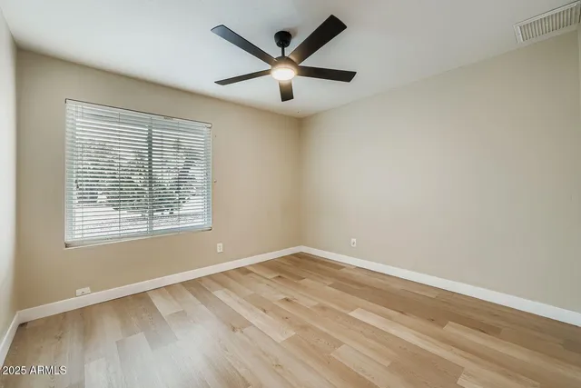 an empty room with ceiling fan and window