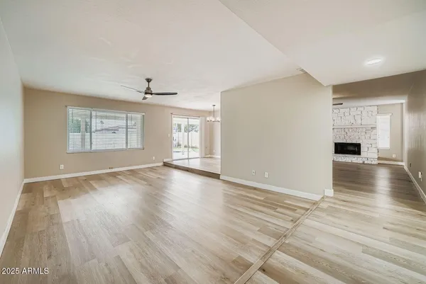 an empty room with wooden floor chandelier and windows